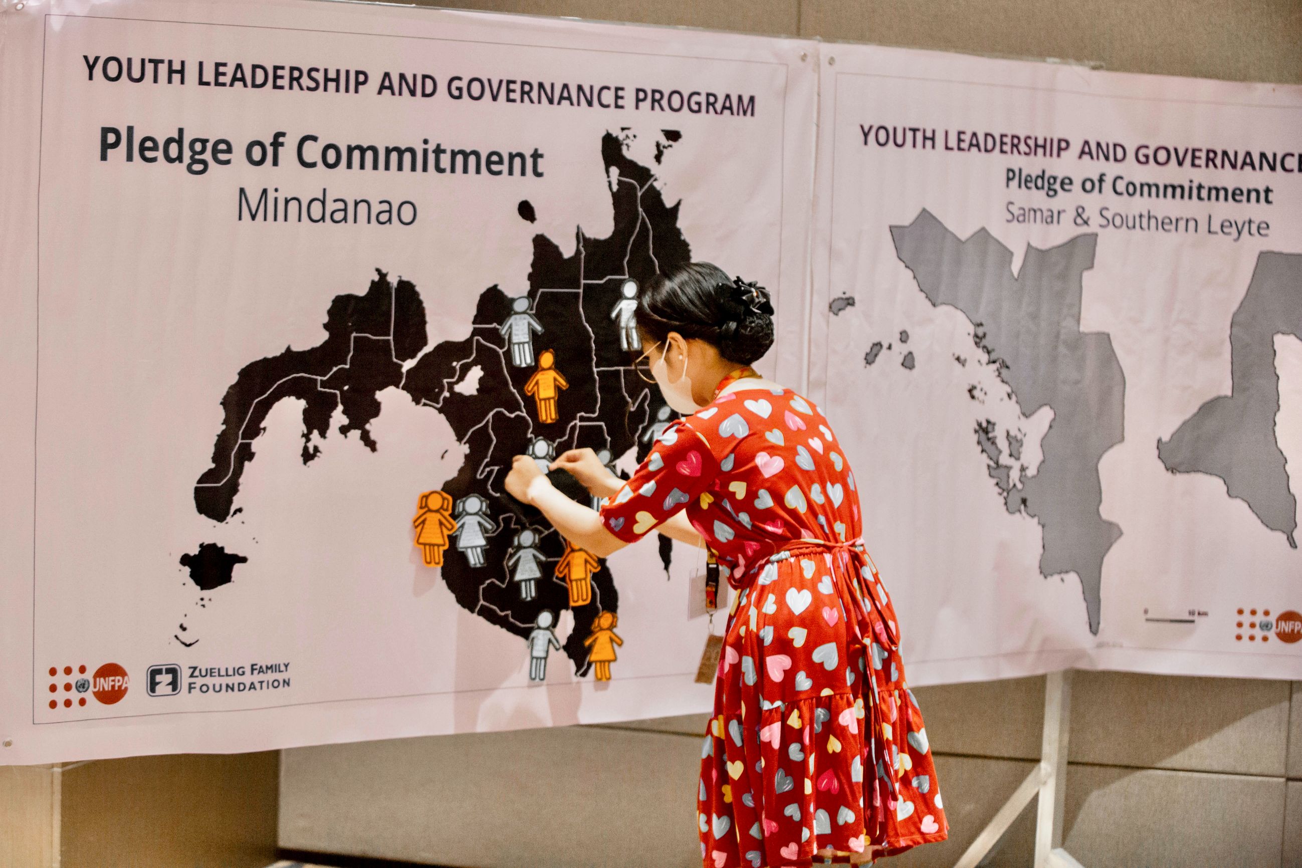 A women sticking a cutout of a girl on a map of Mindanao as part of the event's pledge of commitment.