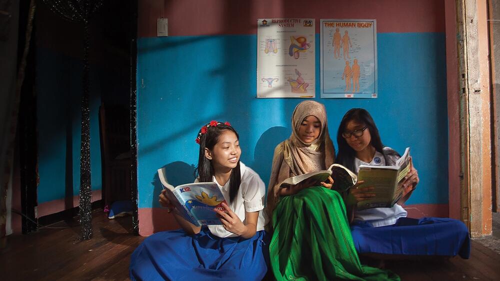 Adolescent girls reading from a lesson book on reproductive health. © UNFPA Philippines/ Froi Rivera