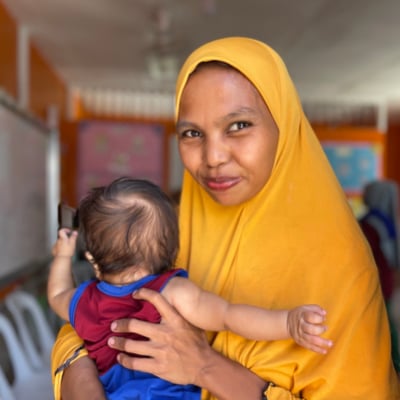 A photo of a mother posing for a photo while holding her baby