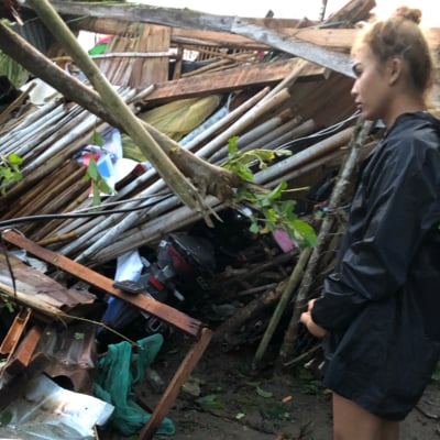 Humanitarian aid worker standing beside a pile of wood debris 